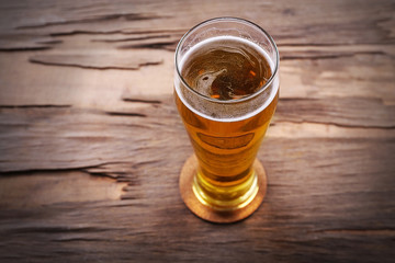 Glass of light beer on wooden background