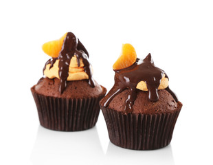 Two tasty cupcakes with slice of mandarin and chocolate, isolated on white
