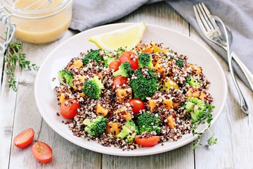 Quinoa salad with broccoli,sweet potatoes and tomatoes on a rustic wooden table.Superfoods concept.Selective focus.