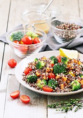 Quinoa salad with broccoli,sweet potatoes and tomatoes on a rustic wooden table.Superfoods concept.Selective focus.