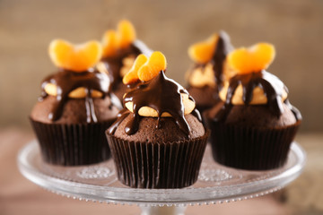 Tasty cupcakes with slice of mandarin and chocolate on wooden background