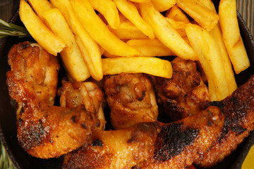 Baked chicken wings with French fries, close up