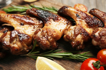 Baked chicken wings with tomatoes and rosemary on cutting board