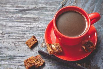 Coffee in a cup on dark wooden table with toast and chocolate . Blurred background . Toned .