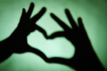 Fototapeta na wymiar Hand shaped heart on green background