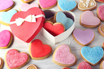 Colorful Valentine heart cookies with present box on wooden table closeup