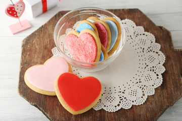 Valentine heart cookies in glass bowl with present box on wooden background