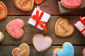 Colorful Valentine heart cookies with present boxes on wooden background