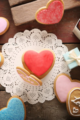 Colorful Valentine heart cookies with present box on wooden table, top view