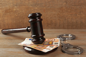 Obraz na płótnie Canvas Law gavel with euro and handcuffs on wooden table background, closeup