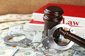 Law gavel with books and handcuffs on dollars background, closeup