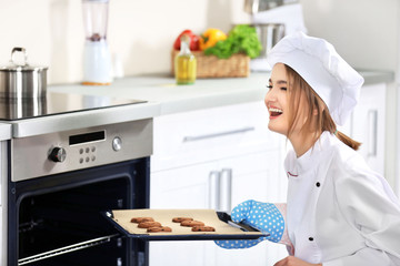 Young woman with pan of chocolate cookies in the kitchen