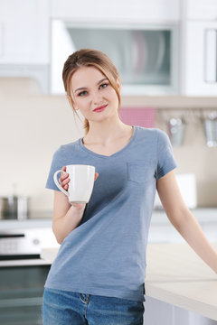 Young woman holding cup in the kitchen