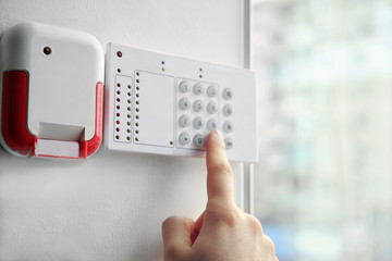 Security alarm keypad with male hand, closeup - obrazy, fototapety, plakaty