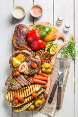 Grilled vegetables and steak with salt on wooden board