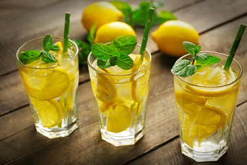 Group of lemonades with lemons and mint on wooden table background