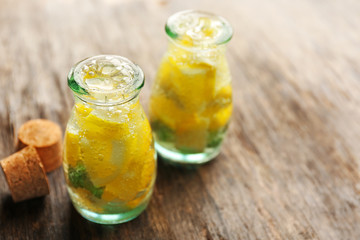 Jars of lemonade with lemon on wooden table background, closeup