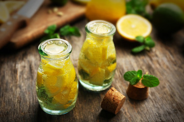 Composition of jars with lemonade, lemons and mint on wooden table background