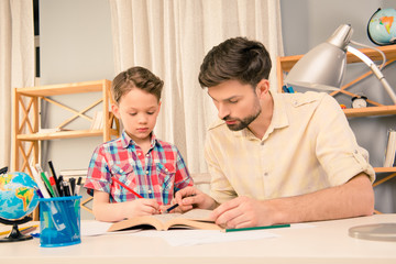 Young father helping his little son with homework