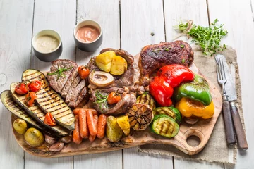 Poster Gegrilltes Gemüse und Steak mit Kräutern auf weißem Tisch © shaiith