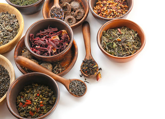 Variety of dry tea in pots and wooden spoons isolated on white