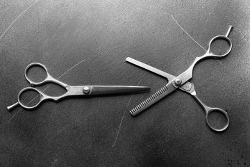 Professional metal scissors lying in two different positions on the grey surface, top view