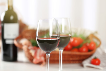 Glasses of red wine with food on blurred background