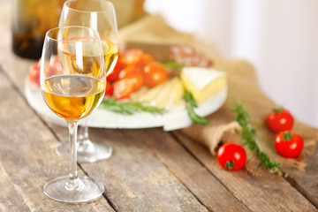 Glasses of wine with food on wooden table closeup
