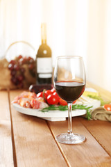 Glass of red wine with food on wooden table closeup
