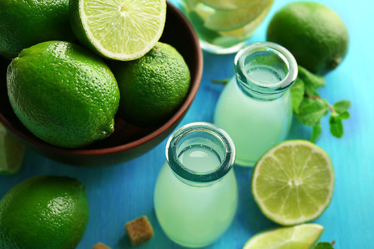 Bottles with lemonade, lime and mint on blue background