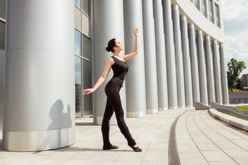 Beautiful graceful ballerina dancing in the front of the buildin