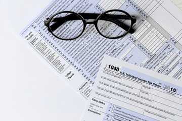 1040 Individual Income Tax Return Form with  black rimmed glasses isolated on the white background, close up