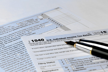 Obraz premium 1040 Individual Income Tax Return Form for 2015 year with a pen to fill on the white desk, close up