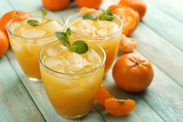 Fresh cocktails with ice, mint and tangerines on the wooden table, close up