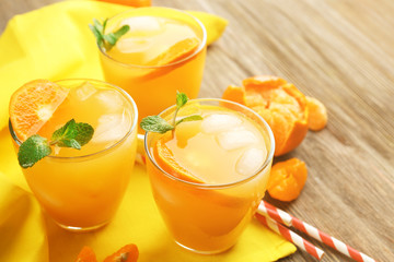 Delicious tangerine cocktails with ice and a mint on a yellow napkin, close up