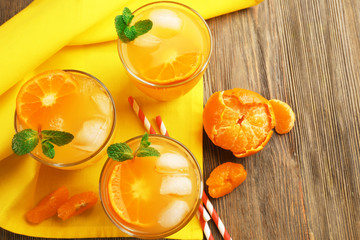 Delicious tangerine cocktails with ice and a mint on a yellow napkin, top view