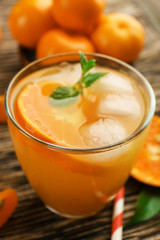 Tangerine cocktail with sliced mandarins, ice, mint on a striped surface, close up