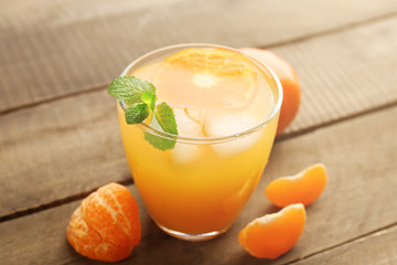 Tangerine cocktail with ice and mint on a wooden surface, close up