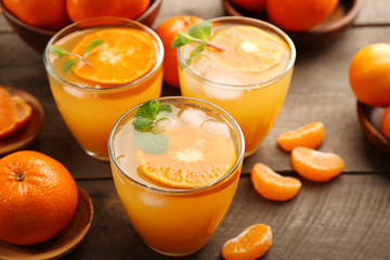Tangerine cocktails with ice and mint on a wooden board, close up
