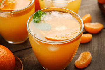 Tangerine cocktails with ice and mint on a wooden board, close up