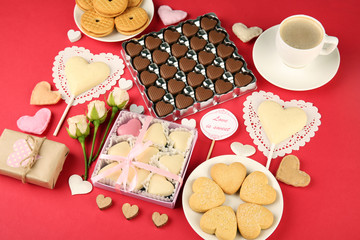 Set of hearts shapes cookies and candies on red table, top view