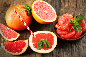 Sliced grapefruits with mint on wooden background, close up