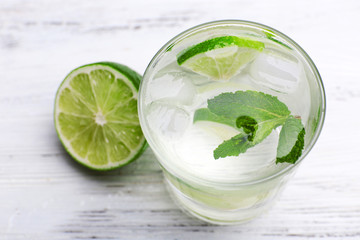 Fresh cocktail with ice, mint and lime on white wooden table background