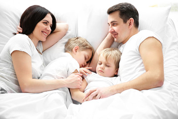 Family smiling in bed under blanket, closeup