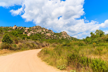A gravel road to Roccapina beach in mountain landscape of Corsica island, France