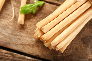 Stack of bread sticks with arugula on wooden table
