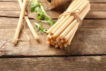 Stack of bread sticks with arugula on wooden table