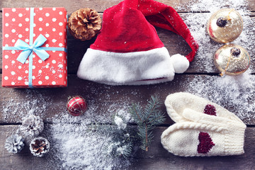 Christmas Santa hat with a gift box and decorations on a wooden table