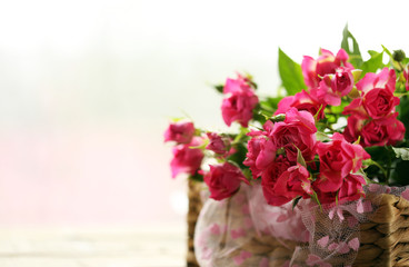 Pink roses in a wicker basket on a table, close up