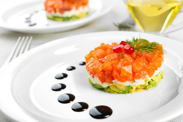 Fresh tartar with salmon, avocado and soy sauce on white plate, close up